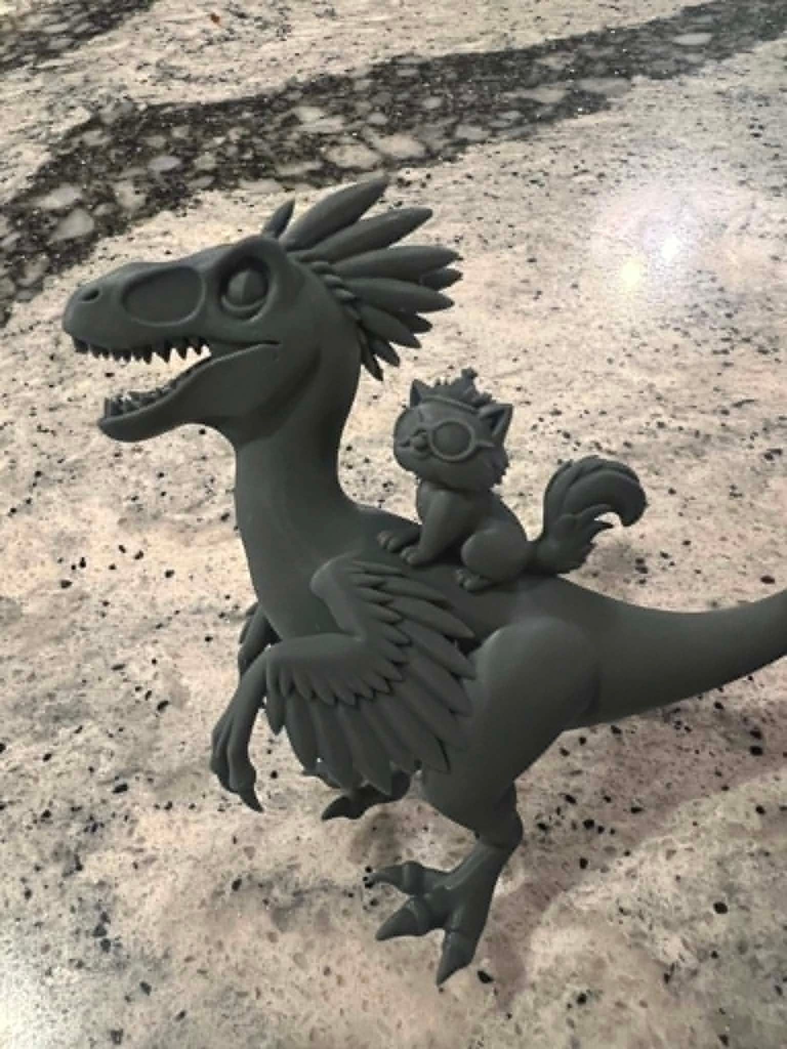 Grey resin 3D print of a velociraptor with a squirrel riding on its back